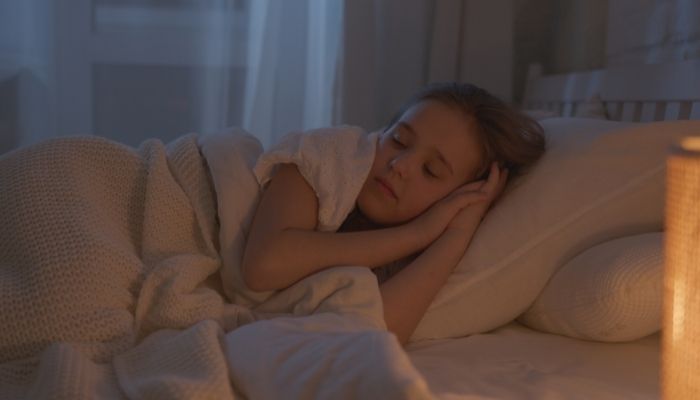 teenage girl sleeping beside a warm lamp