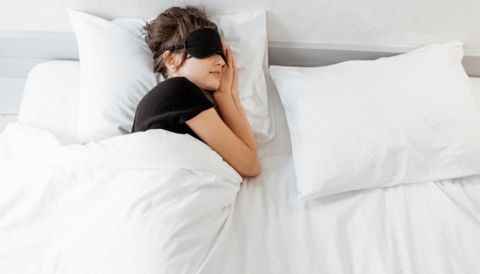 women sleeping in bed wearing black eye mask