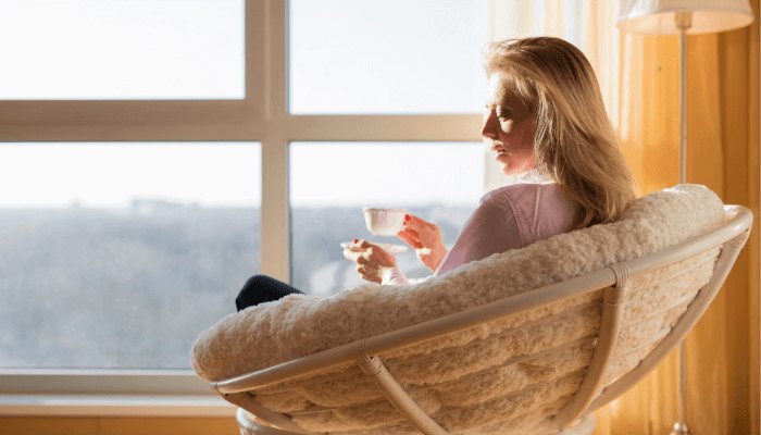 woman having a cup of tea sitting on sofa