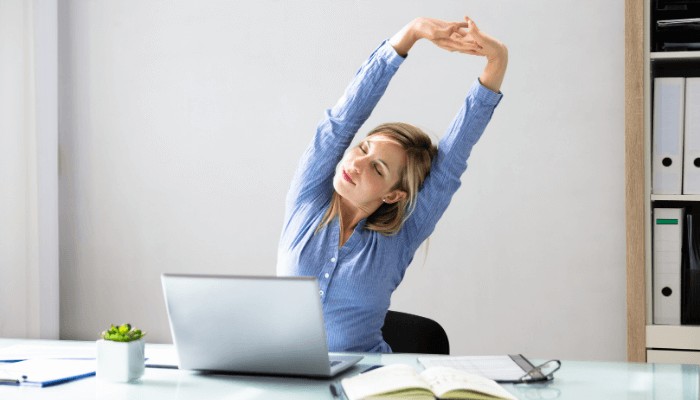 woman streching her hand in front of her work desk