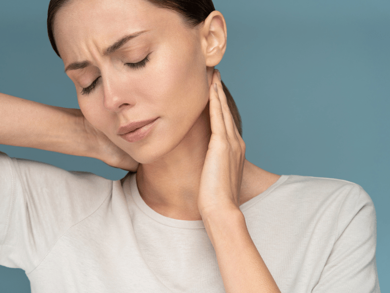 woman holding the back of her head with visible discomfort in her face