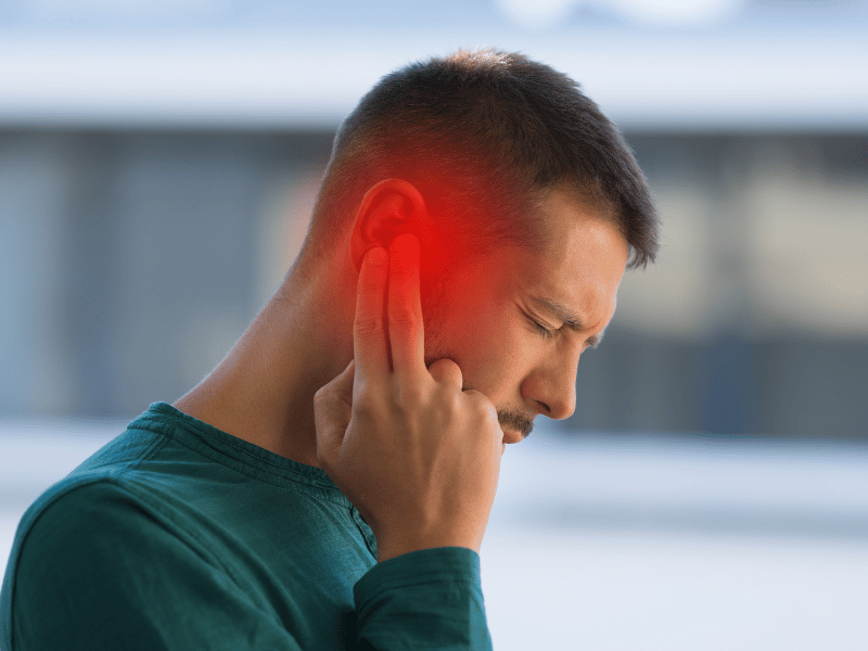 man holding onto his ear in pain due to otitis externa