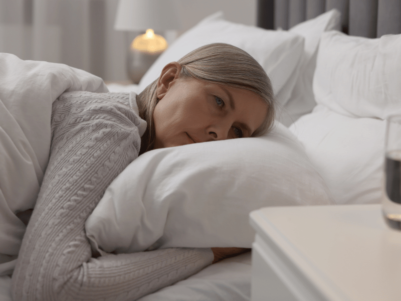 woman with menopause lying in bed and not able to fall asleep