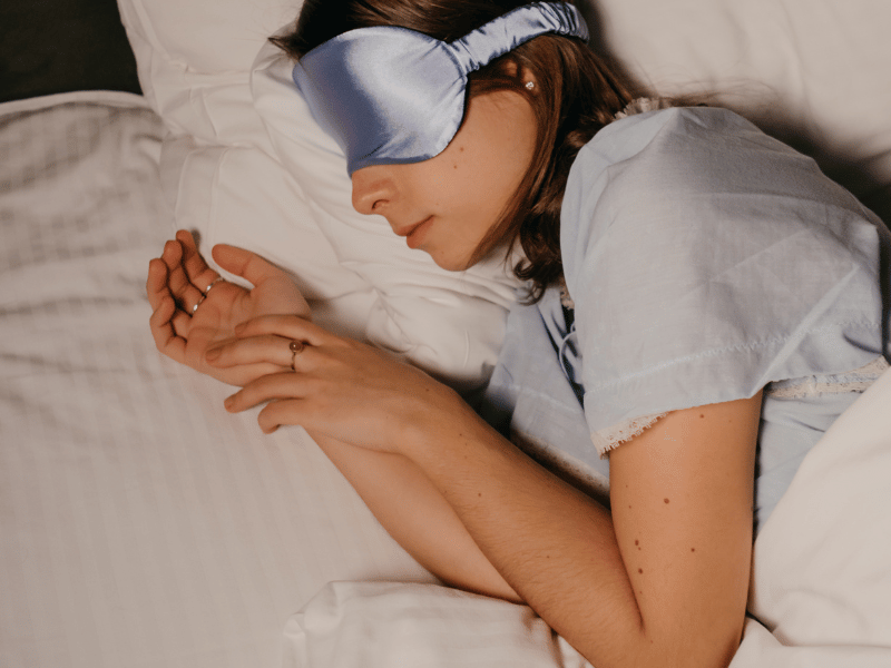 woman sleeping in bed with blue silk eye mask on 