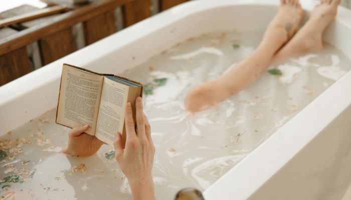 women in bathtub reading a book