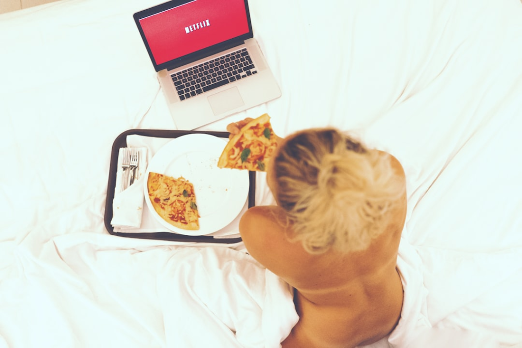 women eating pizza and watching netflix