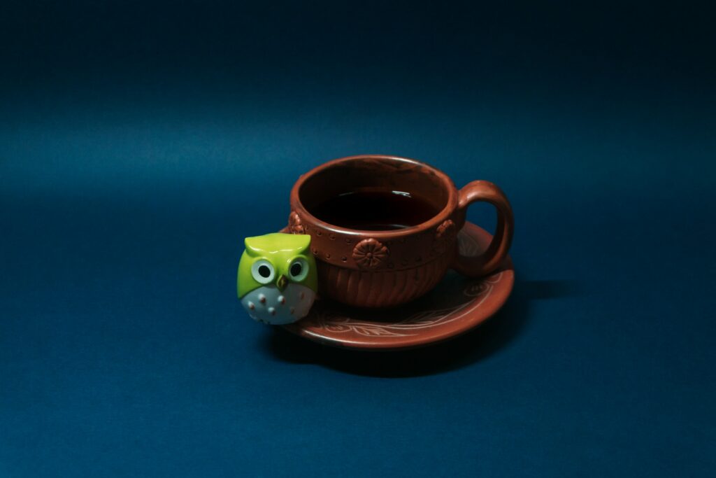 brown ceramic mug with a green owl toy beside it