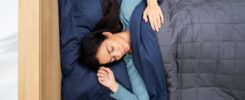 a woman is sleeping in a bed with a blue comforter