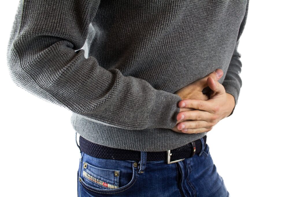 man in jeans holding stomach in pain