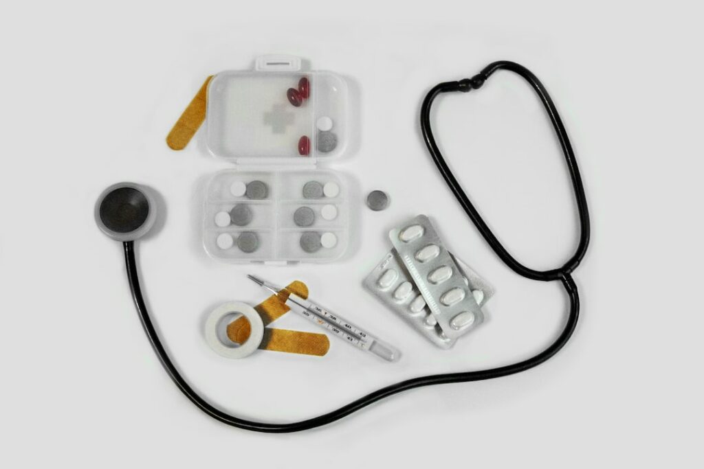 white and black stethoscope on white textile beside some medicine
