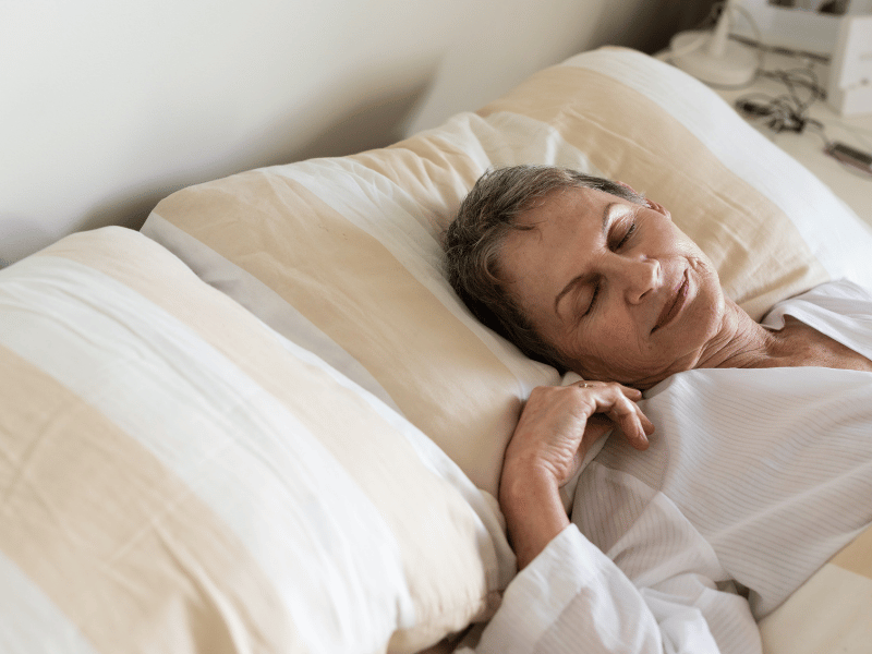 old woman with short hair and eyes closed sleeping with her head on the pillow - sleep quality and head direction