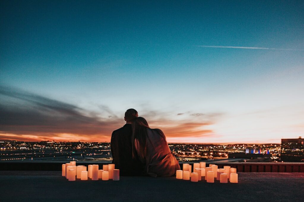 couple sitting on the rooftop facing the city
