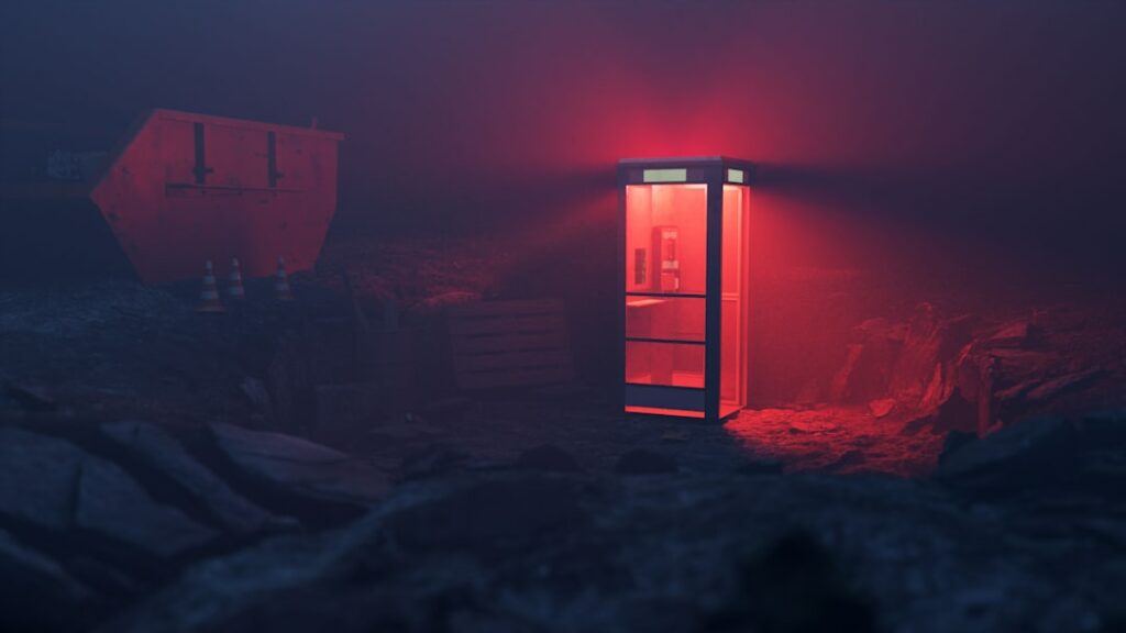 a red light shines on a phone booth in a dark room
