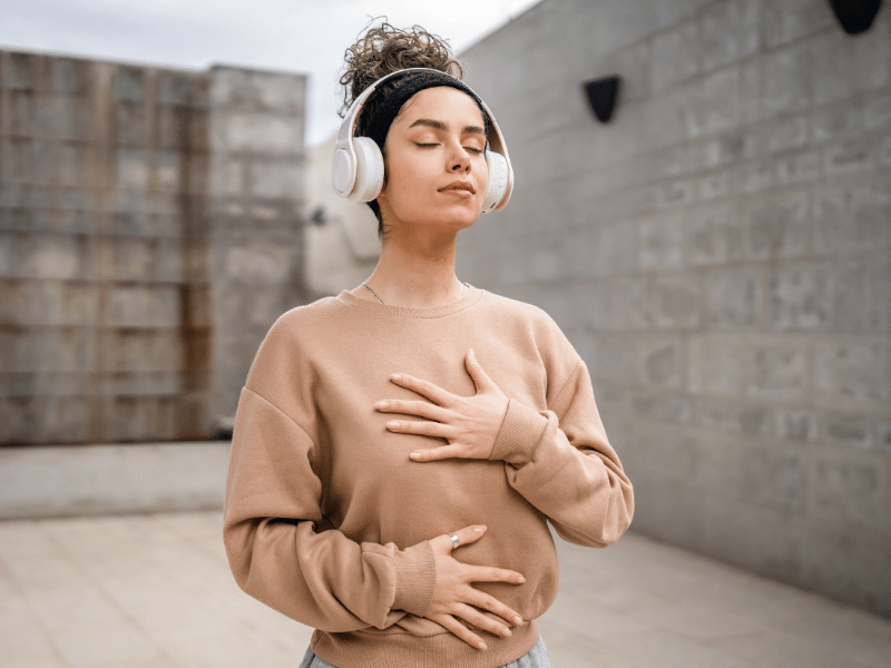 woman touching her chest with eyes closed, focusing on healing which is one of the benefits of meditation