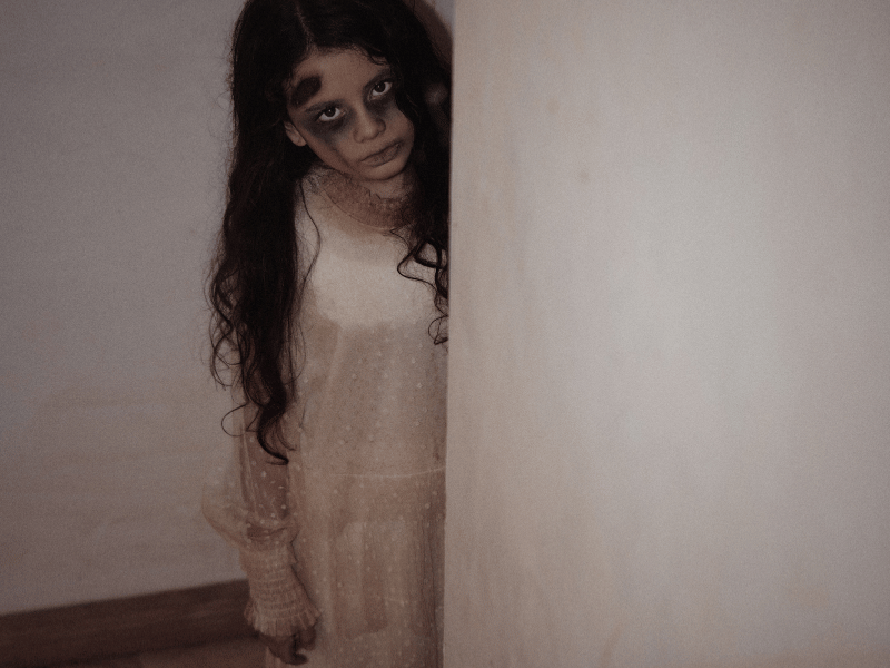 female child ghost with long hair and dressed in white, staring directly.