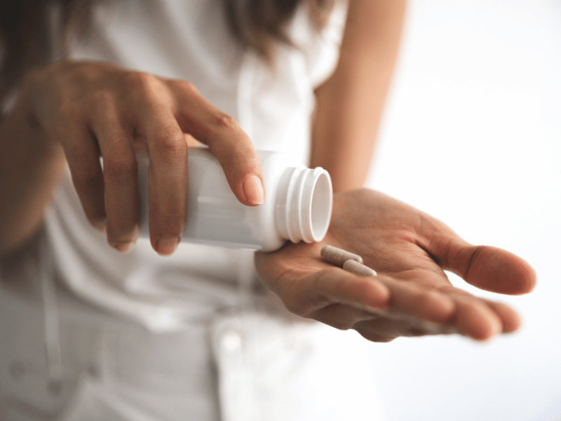 woman holding onto pill bottle with two pills in her palm, when is the best time to take magnesium