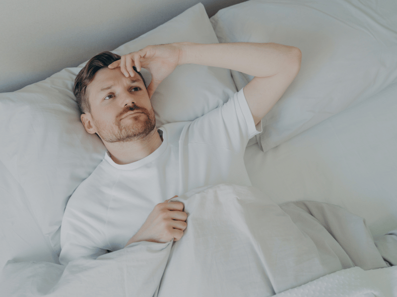 man holding head, not able to sleep due to poor sleep hygiene