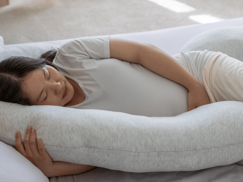 pregnant woman using a pregnancy pillow for sleep