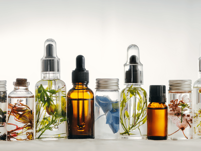 Several glass bottles containing different essential oils, displayed together on a light wooden background.