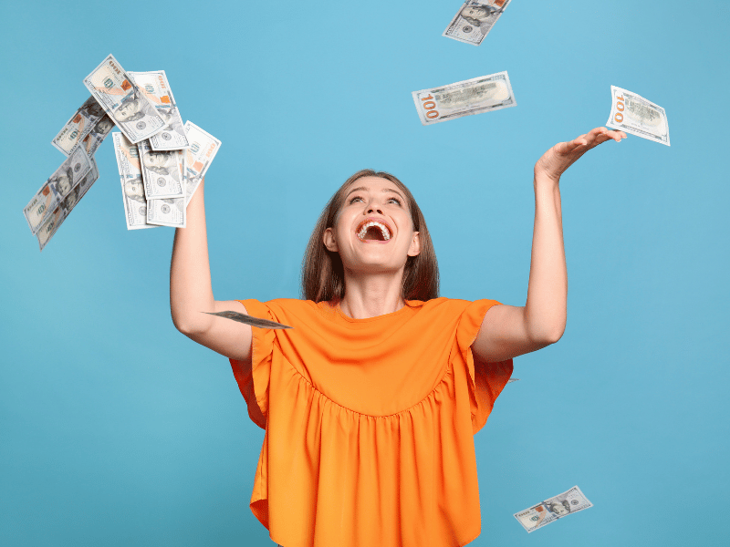 woman looking happy with money flying in the air as part of dreaming about winning lottery